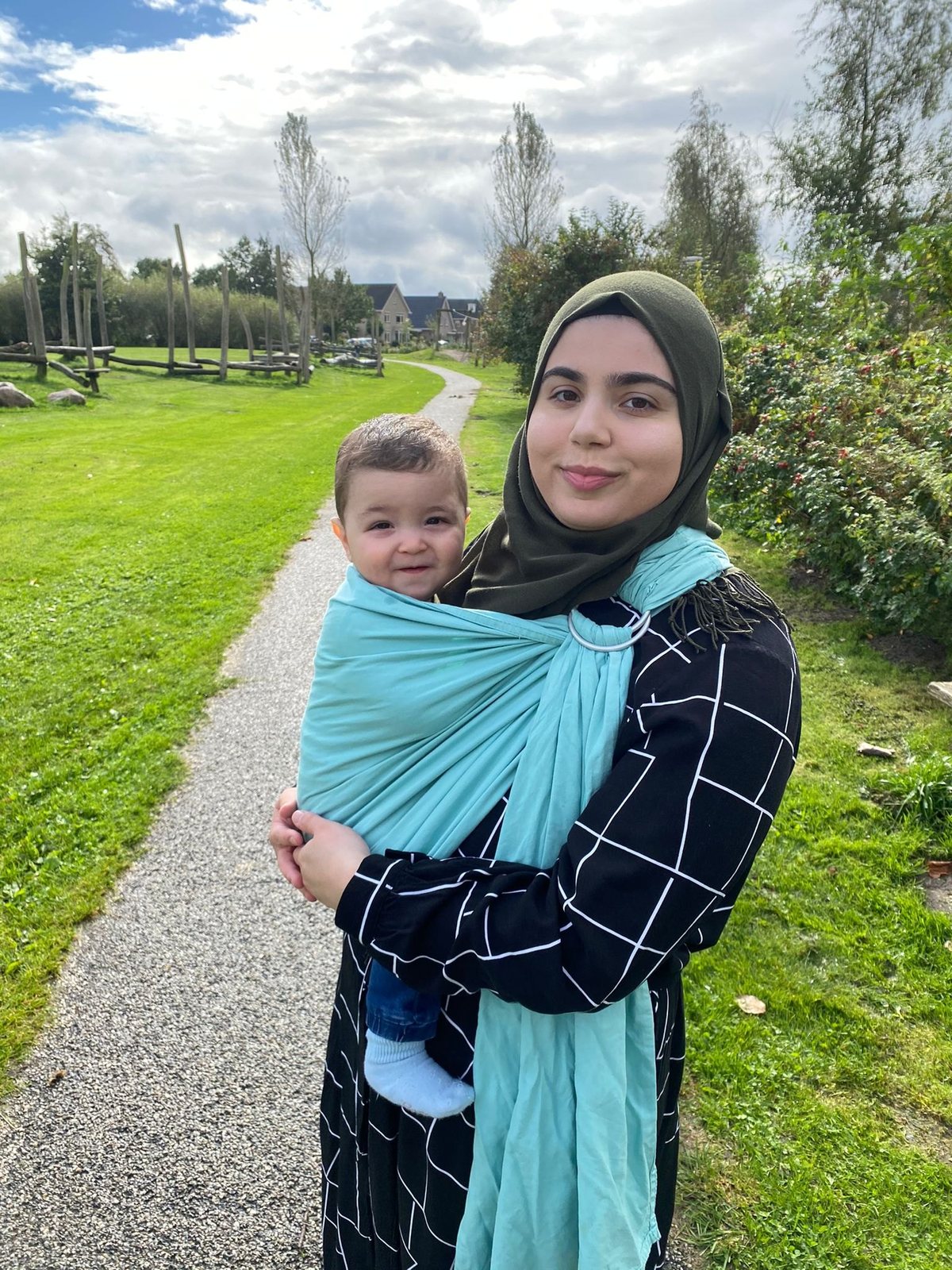 Feride draagt haar kindje in een turquoise ring sling op een wandelpad