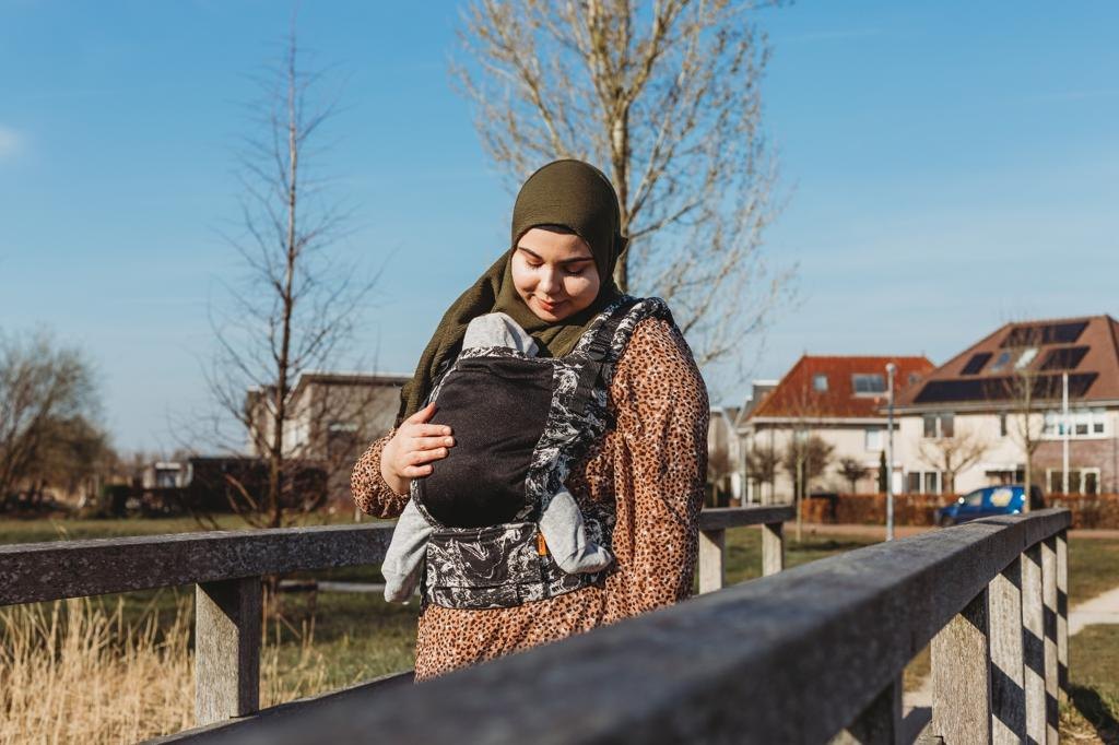 Feride kijkt naar haar baby terwijl zij hem buiten in een draagzak draagt
