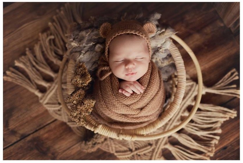 Een pasgeboren baby slaapt ingebakerd in een gebreide doek